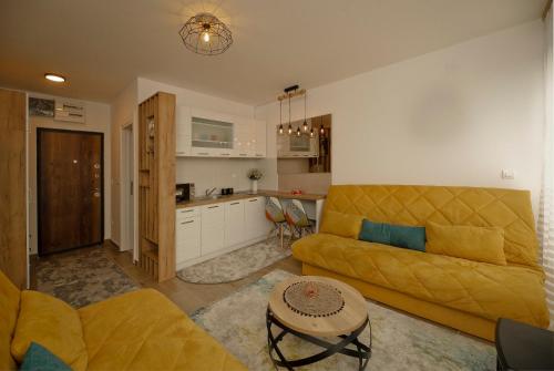 sala de estar con sofá amarillo y cocina en Apartman PETICA Divčibare, en Divčibare