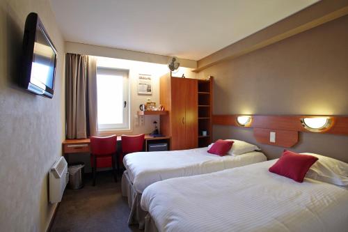 a hotel room with two beds and a desk at Vivaldi Hotel in Westerlo