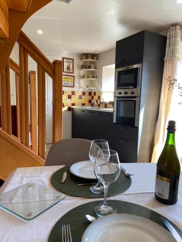 a table with two glasses and a bottle of wine at Gîte Losten Ar Goguès in Trédarzec