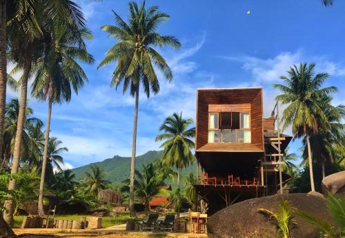 a house on a beach with palm trees at Natuna Dive Resort in Ranai