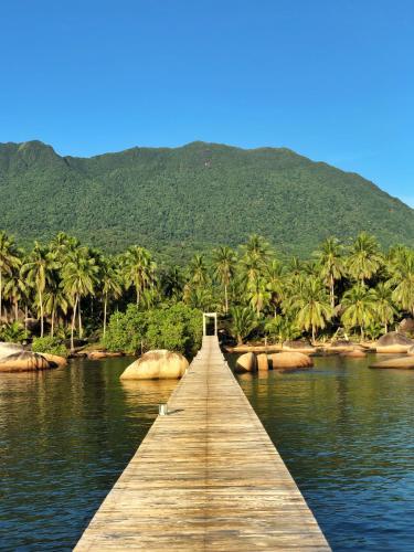 a wooden bridge over a body of water with palm trees at Natuna Dive Resort in Ranai