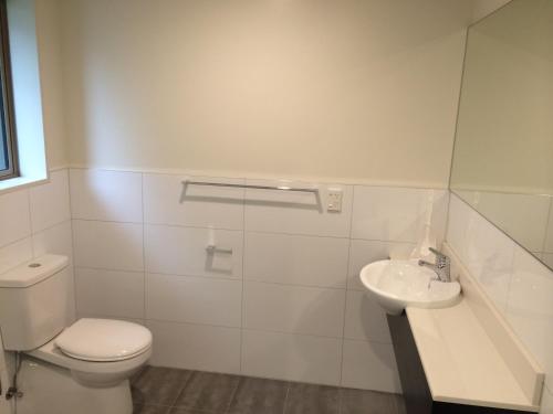 a white bathroom with a toilet and a sink at Rolleston Highway Motel in Rolleston