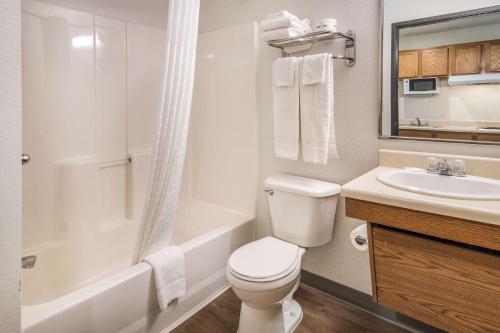 a white bathroom with a toilet and a sink at WoodSpring Suites Denton in Denton