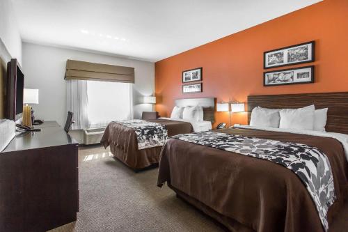 um quarto de hotel com duas camas e uma parede laranja em Sleep Inn & Suites em Lubbock
