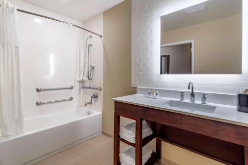 a bathroom with a sink and a tub and a mirror at Comfort Suites in Newnan