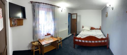 Mały pokój z łóżkiem, biurkiem i telewizorem w obiekcie Pensiunea Gaiu w Albacu