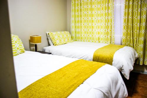 two beds in a room with yellow curtains at Beach Hive 2 in Walvis Bay