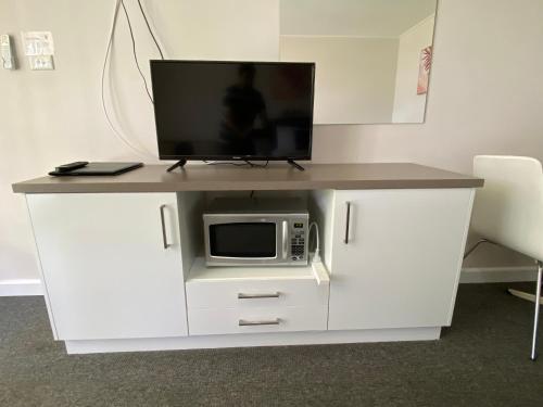 a white cabinet with a microwave and a tv on it at Warrina Motor Inn Wodonga CBD in Wodonga