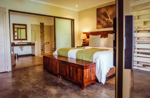 a bedroom with a large bed and a mirror at Bushveld Terrace Safari Hotel, Lodge & Spa in Phalaborwa