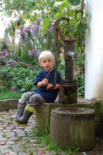 a young boy sitting next to a water fountain at Ferienbauernhof Moarhof in Wittelshofen