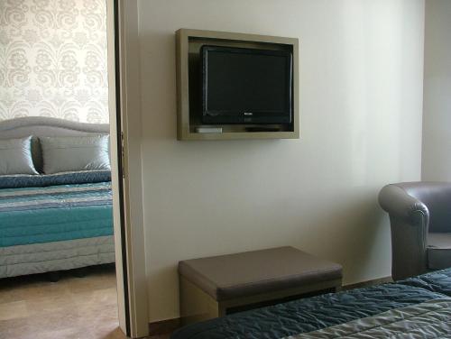サン·ヴィンチェンツォにあるHotel Sabbia D'oroの壁にテレビとベッドが備わる客室です。