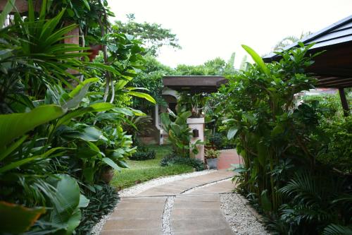 a garden with a walkway leading to a building at Samui Jasmine Resort - SHA Plus in Lamai