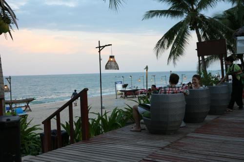 people sitting on a deck looking at the beach at Samui Jasmine Resort - SHA Plus in Lamai