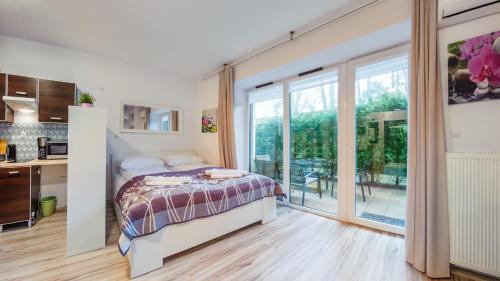 um quarto com uma cama e uma grande janela em Apartamenty Sun & Snow Willa Park em Dziwnów