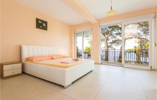 a bedroom with a white bed and large windows at Awesome Home In Brela With Jacuzzi in Brela