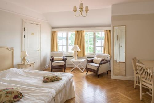 a bedroom with a bed and chairs and a living room at Möckelsnäs Herrgård in Diö