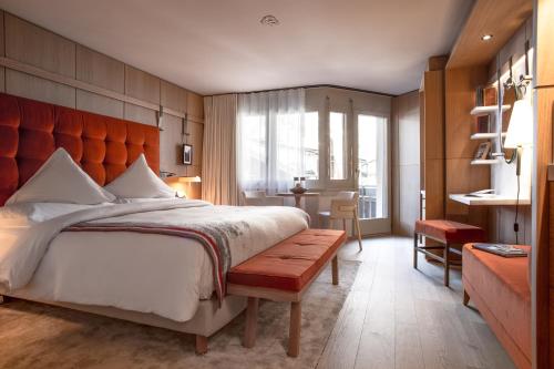 a bedroom with a large bed and a bench at Schweizerhof Zermatt - a Small Luxury Hotel in Zermatt