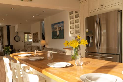 a kitchen with a table with white plates and yellow flowers at Hazelmere - Woolacombe-4 Bed-Sleeps 10-TJSHH in Woolacombe