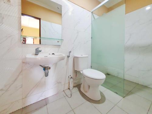 La salle de bains est pourvue de toilettes, d'un lavabo et d'une douche. dans l'établissement Graha Adi Karya Syariah Kartasura RedPartner, à Kartosuro