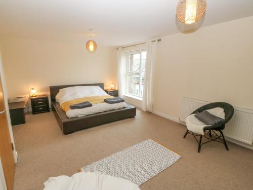 a bedroom with a bed and a chair and a window at Barn End, 9 Stad Clynnog in Llanfairpwllgwyngyll