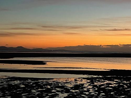 a sunset over the water with mountains in the background at Barn End, 9 Stad Clynnog in Llanfairpwllgwyngyll