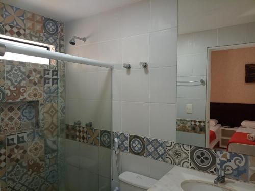 uma casa de banho com um chuveiro, um lavatório e um espelho. em Pousada Aquarela Do Brasil em Maceió