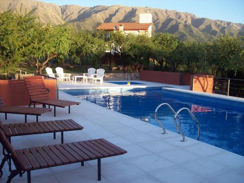 a swimming pool with two benches and chairs next to it at Cabañas La Casa de Adriana in Merlo