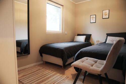 a bedroom with two beds and a mirror and a chair at Stijlvol ingerichte bungalow aan de Westerschelde in Baarland