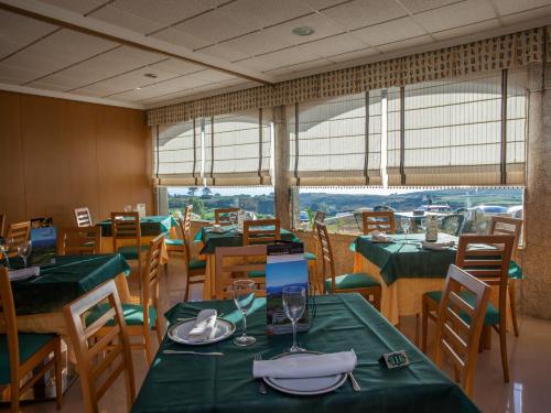 a restaurant with tables and chairs with green tablecloths at Hotel Oca Vermar in Aios