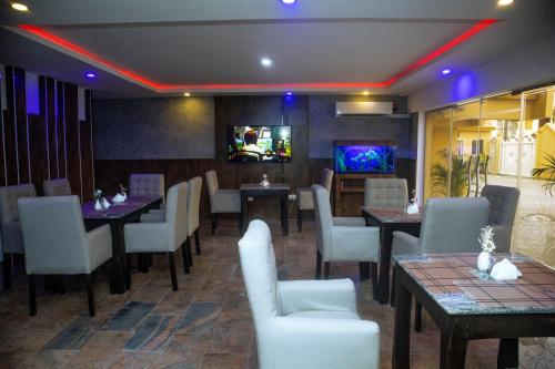 a restaurant with tables and chairs and a tv at PRESKEN HOTELS @FAJODD-4 in Ikeja