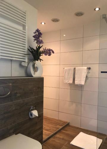 a bathroom with a toilet and a vase with purple flowers at Appartement Modern Egmond in Egmond aan Zee