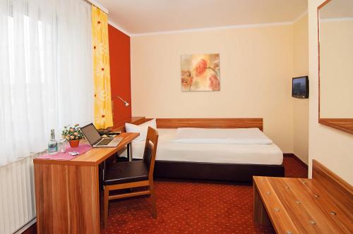 ein Hotelzimmer mit einem Bett und einem Schreibtisch mit einem Laptop in der Unterkunft Jägerheim in Nürnberg