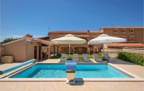 - une piscine avec des chaises et des parasols sur une maison dans l'établissement 2 Bedroom Gorgeous Apartment In Hr-52215 Vodnjan, à Vodnjan