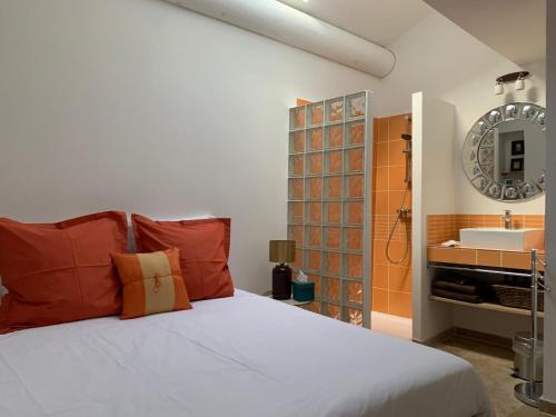 a bedroom with a bed and a bathroom with a sink at La Maison du Courtil, Amande-Olive in Moustiers-Sainte-Marie
