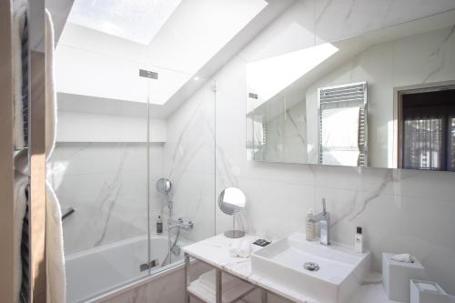 a bathroom with a sink and a tub and a mirror at Schweizerhof Zermatt - a Small Luxury Hotel in Zermatt