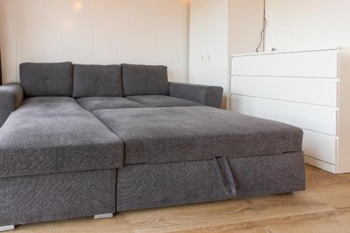 a gray couch in a living room next to a dresser at Reykjavík Outskirts - Minimalist Escape in Vogar