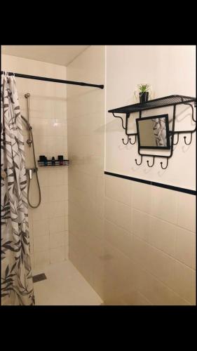 une salle de bain avec une douche avec un lavabo et un miroir dans l'établissement Gîte Baie Bonheur, à Genêts