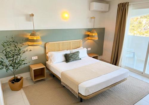 a bedroom with a bed with two lamps and a plant at Club Menorca - Solo Adultos in Cala en Porter
