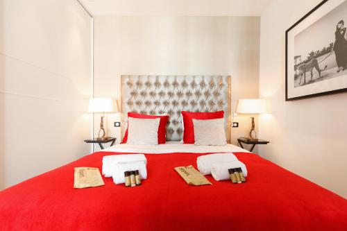 - une chambre avec un lit rouge et 2 serviettes dans l'établissement L'attique des Artistes YourHostHelper, à Cannes