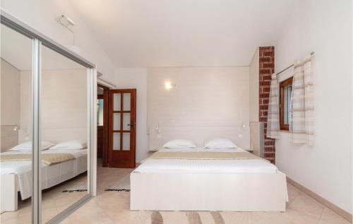 a white bedroom with two beds and a mirror at Pet Friendly Home In Cara in Zavalatica