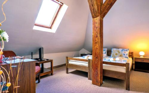 a attic room with a bed and a window at Hotel Stará škola na Šumavě in Hořice na Šumavě