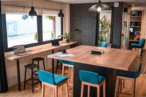 ein Büro mit einem großen Holztisch mit blauen Stühlen in der Unterkunft Kyriad Saint Brieuc - Tregueux in Tregueux