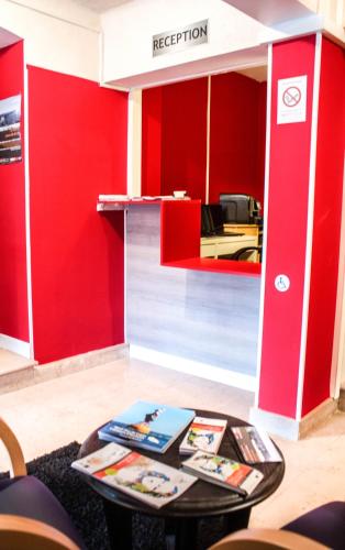 un bureau avec des murs rouges et une table avec des ordinateurs portables dans l'établissement Hotel Le Jardin, à Lens