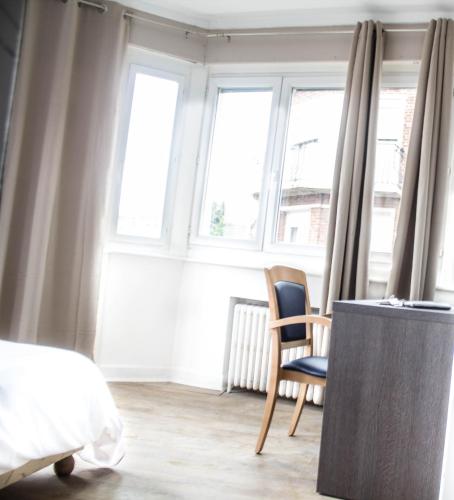 une chambre avec un lit, une chaise et des fenêtres dans l'établissement Hotel Le Jardin, à Lens