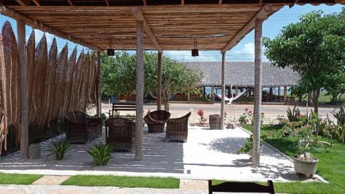 un grupo de sillas bajo un pabellón de madera en Pousada e Restaurante do Francisco en Icapuí