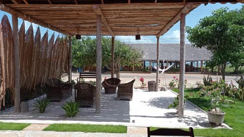 a group of chairs under a wooden pavilion at Pousada e Restaurante do Francisco in Icapuí