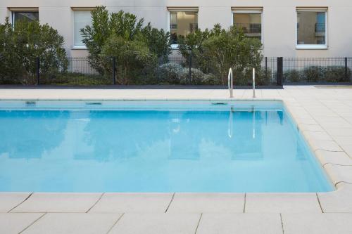 a large blue swimming pool in front of a building at Aparthotel Adagio Access Bordeaux Rodesse in Bordeaux