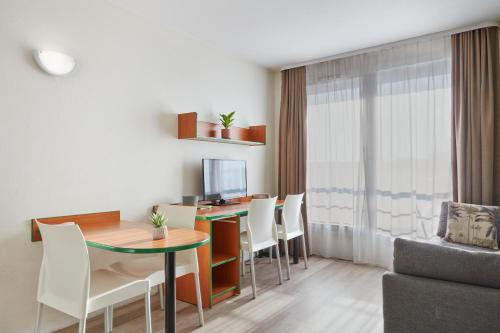 un salon avec une table et des chaises dans l'établissement Aparthotel Adagio Access Bordeaux Rodesse, à Bordeaux