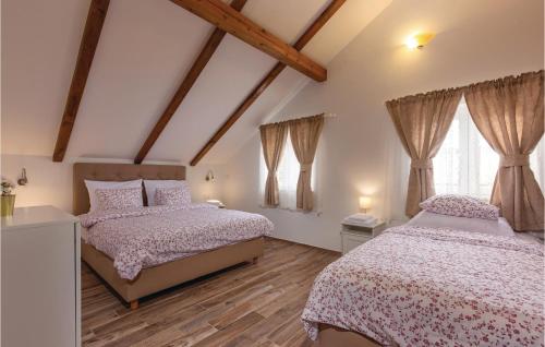 two beds in a bedroom with wooden floors and windows at Stunning Home In Gospic With Sauna, Wifi And Indoor Swimming Pool in Gospić