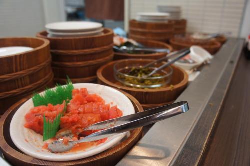 a plate of food on a counter with bowls of food at Dormy Inn Hakata Gion in Fukuoka
